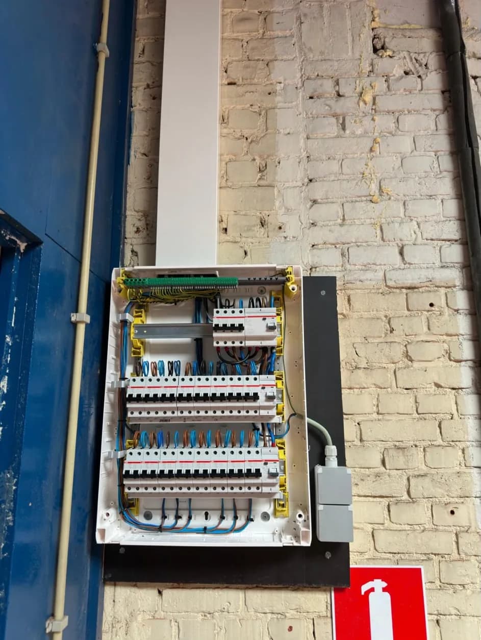 Nieuw verdeelbord met drie rijen automaten in een bedrijfshal, de leidingen in een witte kabelgoot naar boven